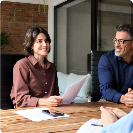 deux clients, une femme tenant des papiers et un homme, souriant à leur experte-comptable